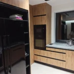 Nowoczesna kuchnia na wymiar z ciemnymi sprzętami i frontami w kolorze drewna – Dariusz Kamińsk