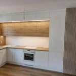 Biała kuchnia na wymiar z drewnianym blatem, lamelami i podświetleniem LED – Dariusz Kamiński