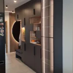 Zabudowa wejściowa z ciemną płytą meblową i dekoracyjnym półokrągłym podświetleniem LED – nowoczesny projekt mebli na wymiar w Olsztynie